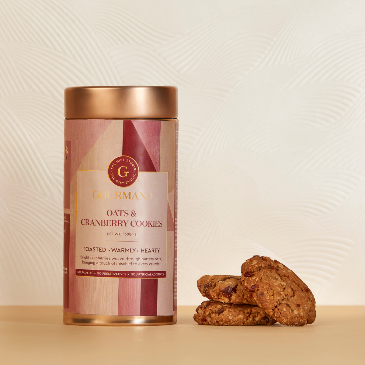 The Gift Studio Oats & Cranberry Cookies in a gold tin with cookies beside it.