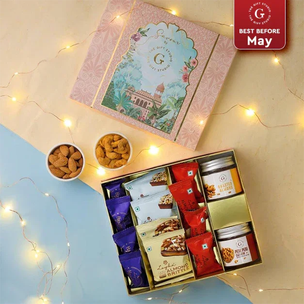 Assorted snack gift box with nuts, brittle bars, and jars, festive lights background