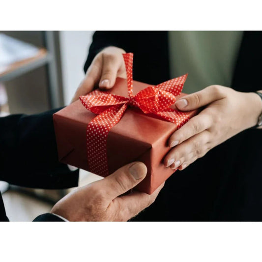 Person giving a red gift box with a polka dot ribbon, perfect for special occasions