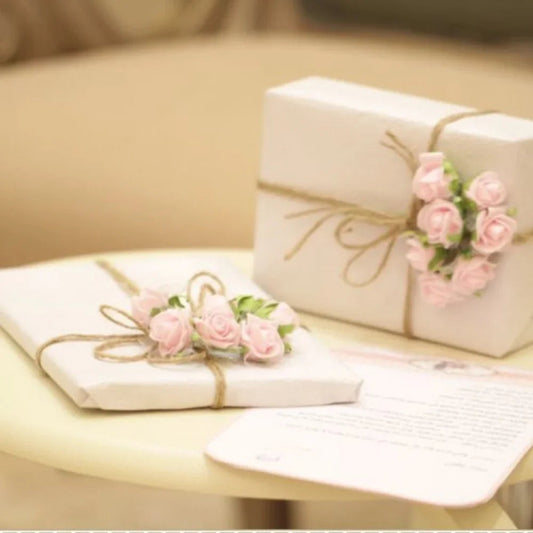 Elegant gifts wrapped in white paper with twine and pink flower decorations on a table