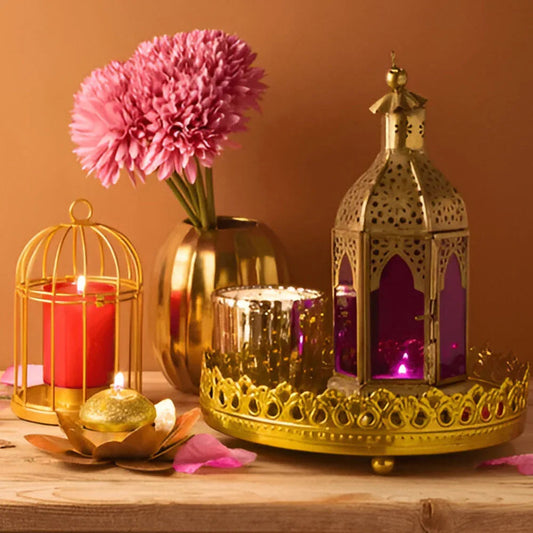 Festive candle arrangement with gold lanterns, pink flowers, and decorative tray