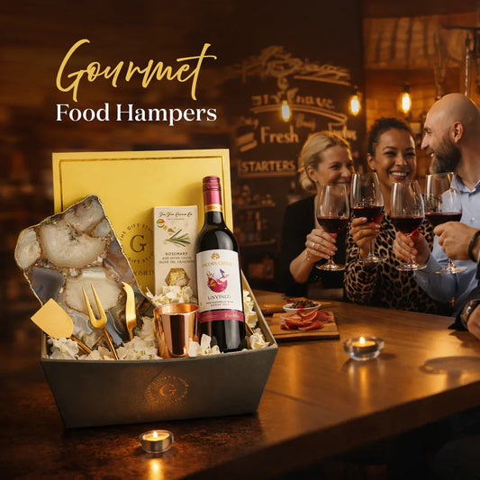 Gourmet food hamper with wine, crackers, and utensils on a table, people enjoying drinks