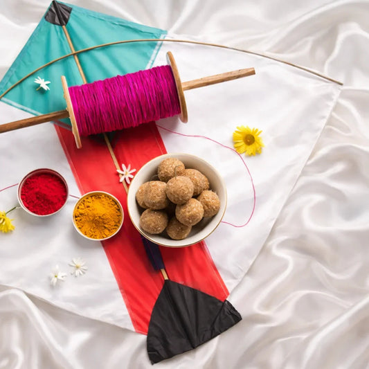 Colorful kite with pink string, ladoos, red and yellow powders, flowers on silk cloth