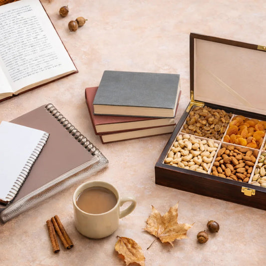 Assorted dry fruits gift box with books, notebooks, coffee, and autumn leaves on table