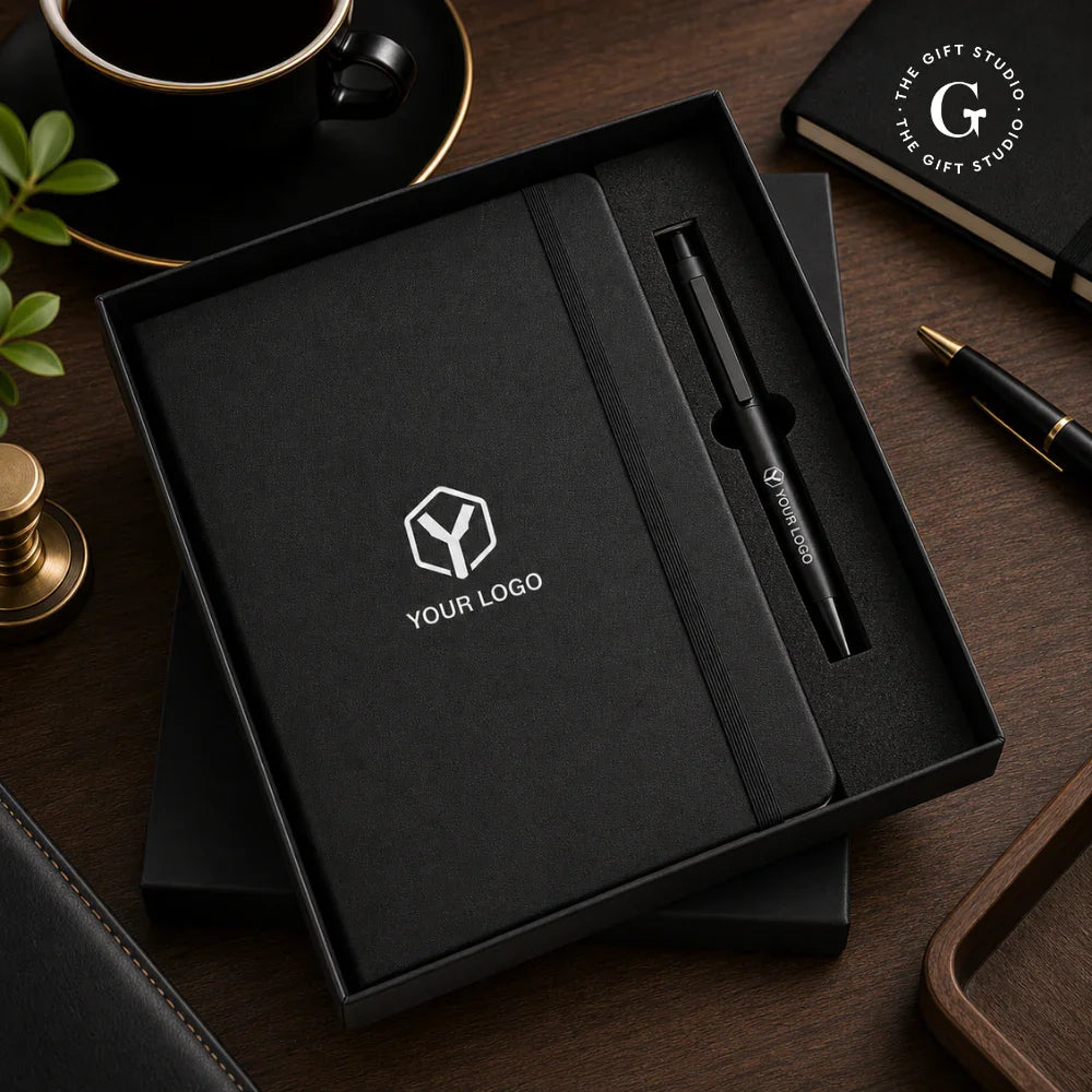 TGS Black notebook with pen and logo in a box on a desk 