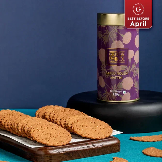 Baked Nolen Matthi cookies stacked on a tray next to a decorative purple tin.