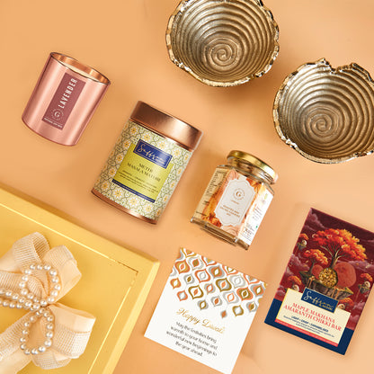 Delightful Diwali Hamper by The Gift Studio featuring gourmet treats, a candle, and gold bowls.
