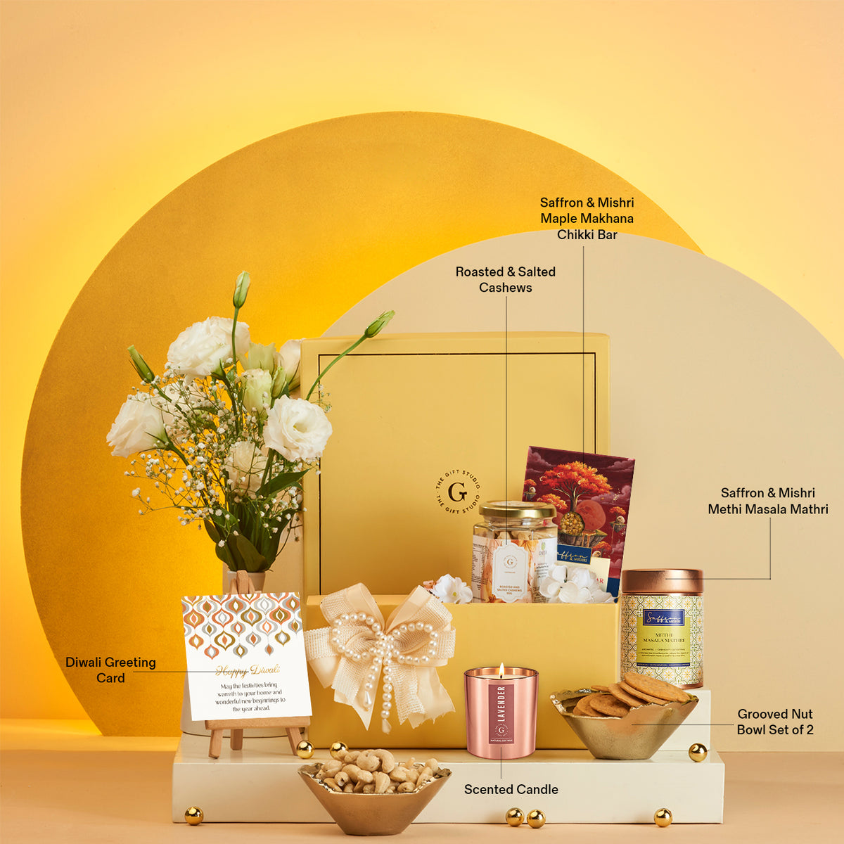 Delightful Diwali Hamper by The Gift Studio featuring gourmet treats, candle, and white flowers.