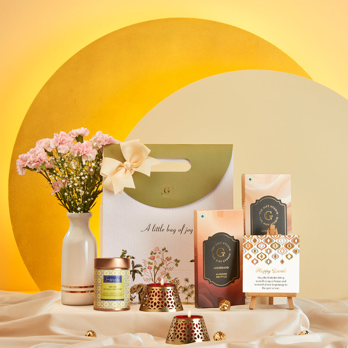 Diwali Treat Bag gift hamper from The Gift Studio with sweets, candles, and flowers.