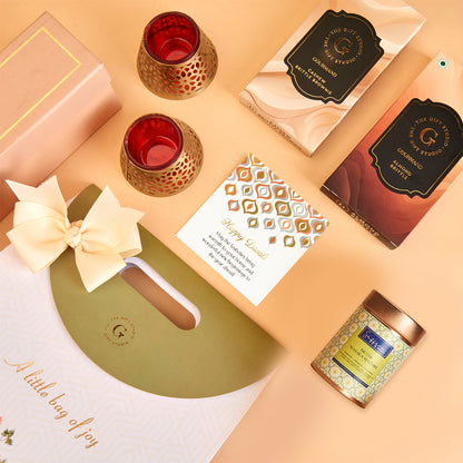 The Gift Studio Diwali Treat Bag featuring gourmet sweets, candles, and a greeting card.