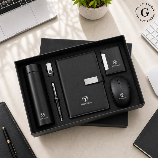 TGS Black office gift set with branded items on a wooden surface like pen, bottle, non-branded mouse, notepad, keychain and diary.