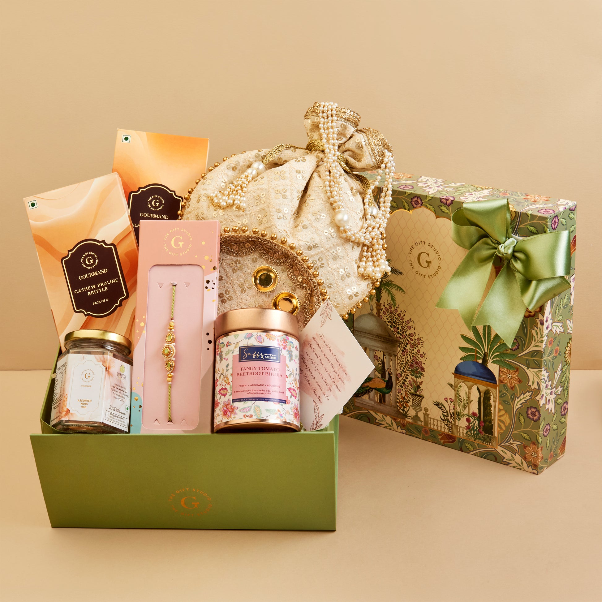 A luxury gift hamper set from the brand  featuring a green presentation box filled with premium items including a gold-embellished drawstring pouch, a Rakhi, and snacks in a gift box.
