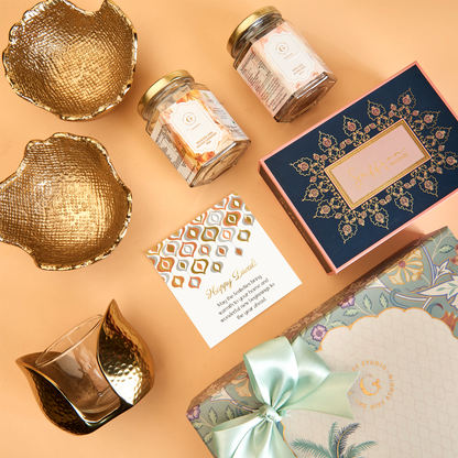 The Diwali Soirée Hamper by The Gift Studio featuring gold bowls, gourmet jars, and a gift box.